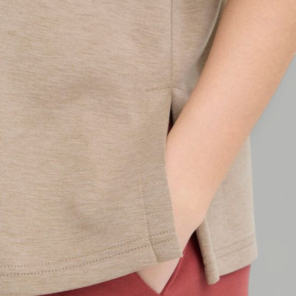 Close-up of a person wearing a beige shirt with a gray background